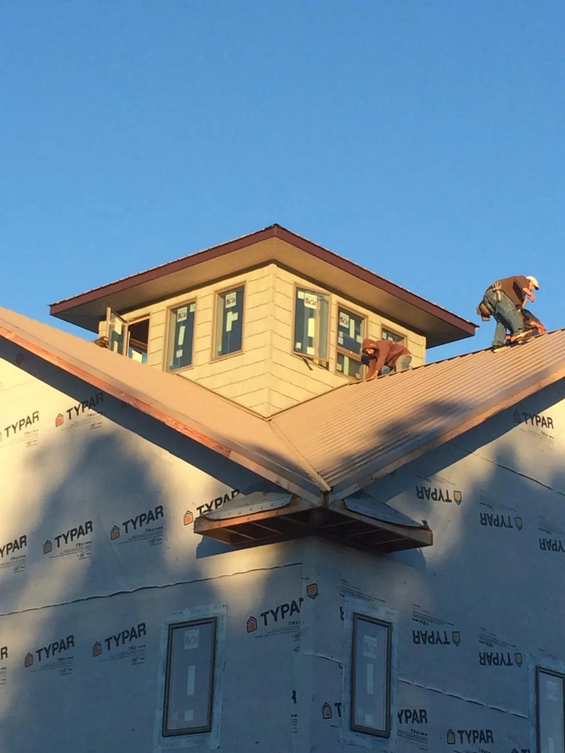 Roofers working around a rooftop cupola on a new metal roof at sunset — Roof Waterproofing in Hinton by Roofing Brothers